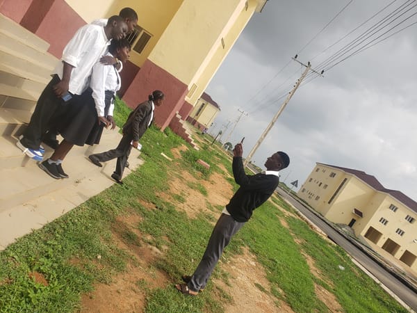 Four people gather on building stairs in Gumel, Nigeria