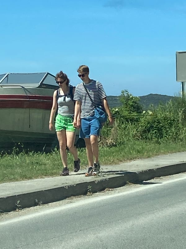 Pedestrians walk roadside in Prijevor, Montenegro morning scene