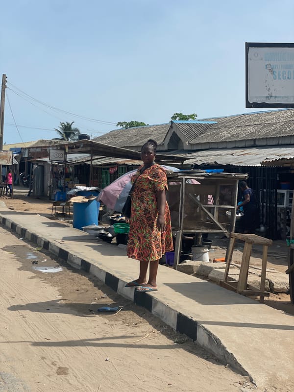 Woman stands among small shops in Itoga, Nigeria