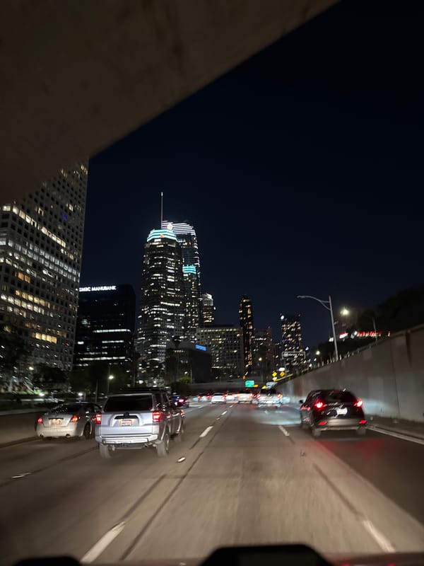 Early morning traffic flows beneath illuminated LA skyline