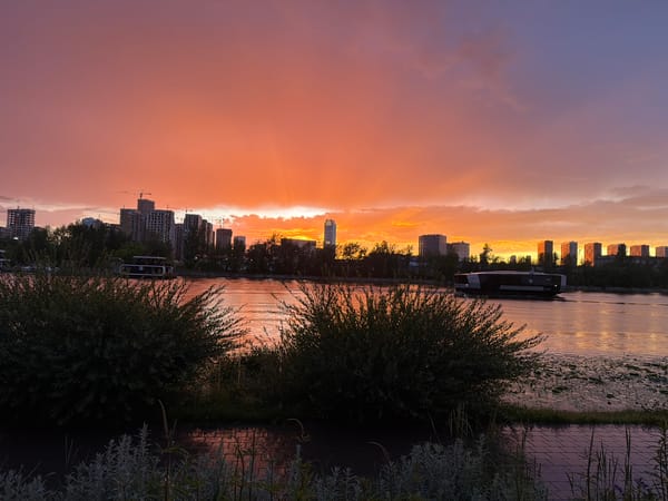 Moscow riverfront at golden hour, cranes and a rainbow