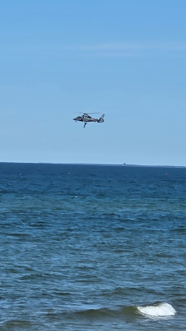 Helicopter rescue operation plays out over the ocean near a beach