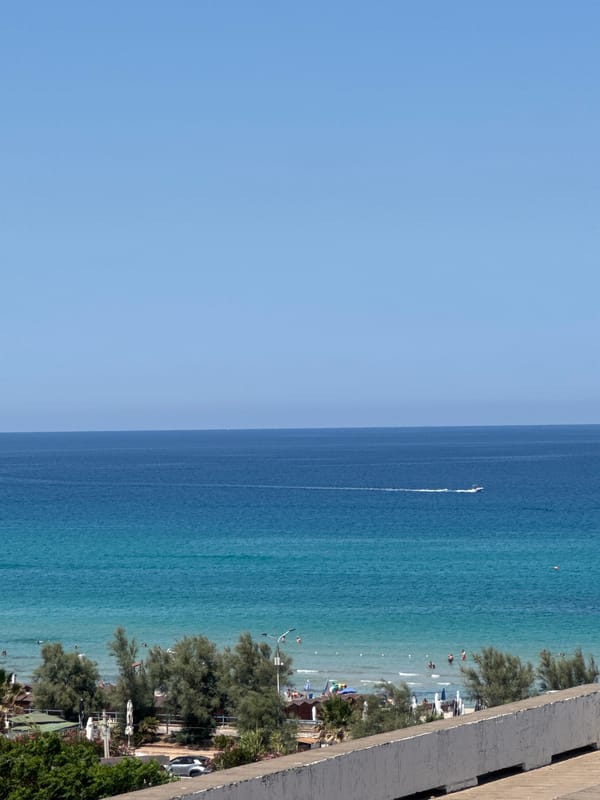Sailboats, turquoise water, and rocky coast at Isola delle Femmine