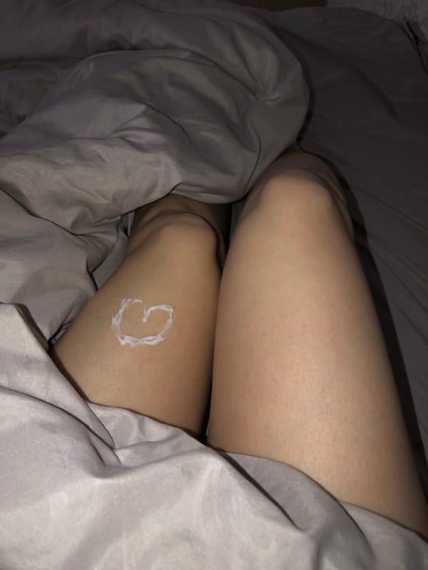 Person creates heart design with lotion on leg in Noviy