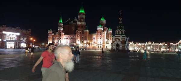 Nighttime plaza scene by a lit Gothic waterfront