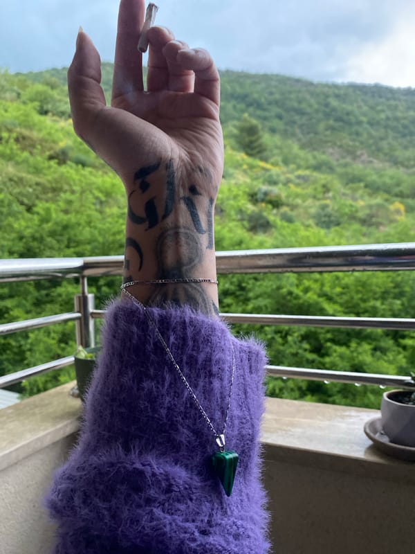 Person smokes on balcony overlooking Montenegro mountains