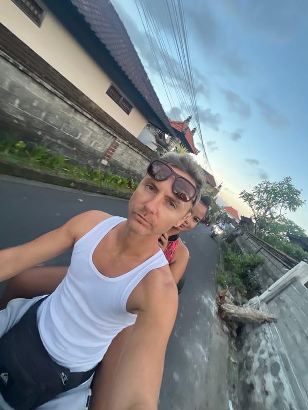 Couple rides motorcycle through Sukawati streets on overcast day