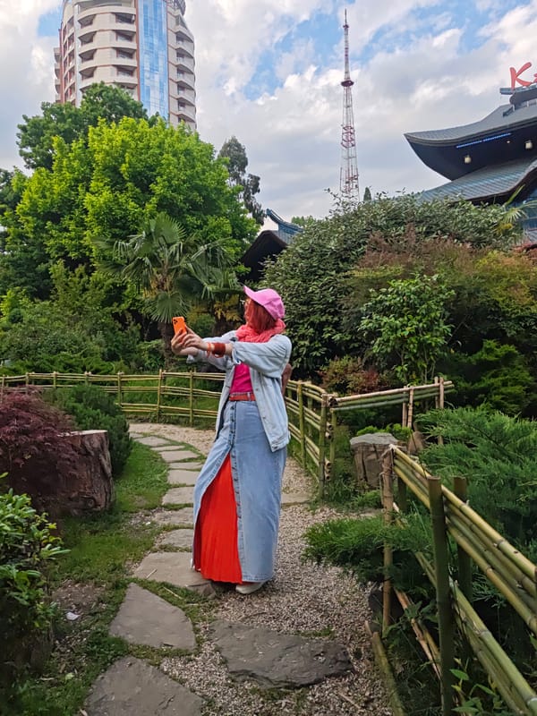 Woman Takes Selfies in Sochi Garden Near Restaurant