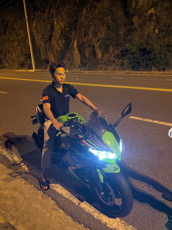 Young man poses with motorcycle at roadside during night