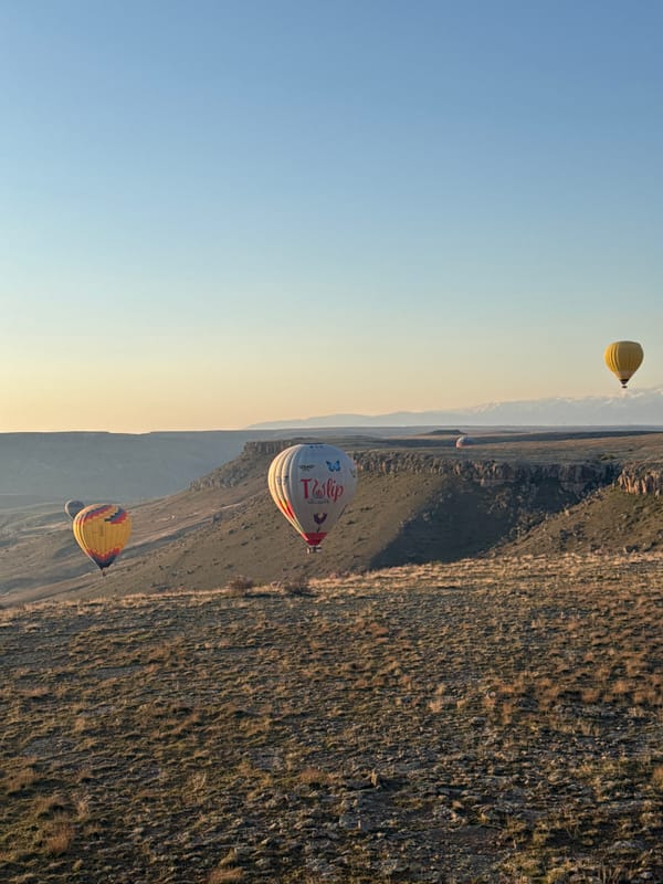 Hot air balloons drift over Turkish landscape at sunrise