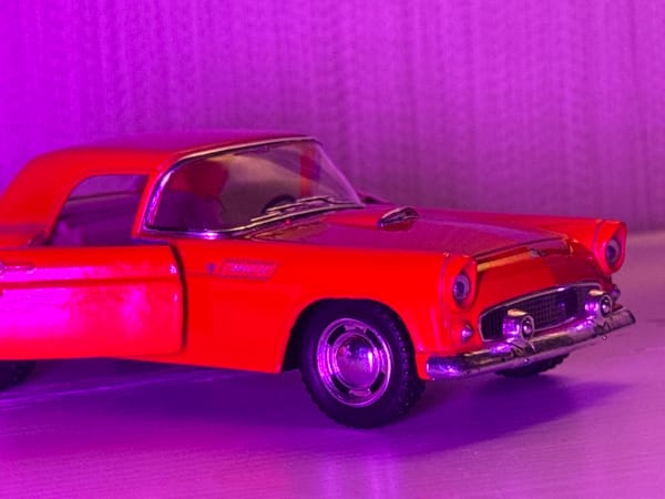 Red vintage toy car styled under moody purple light