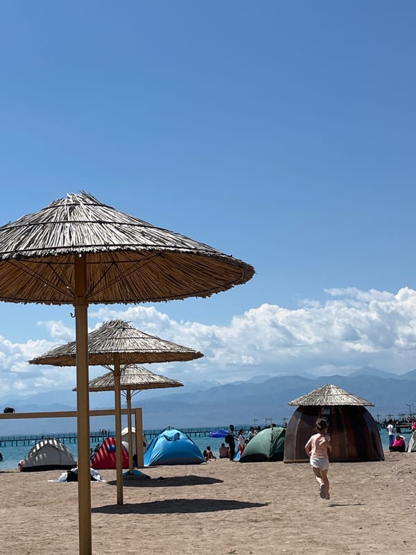 Sunny day at Balykchy's thatched-umbrella beach on Issyk-Kul