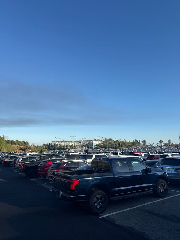 Packed stadium parking lot stretches toward the venue under blue skies