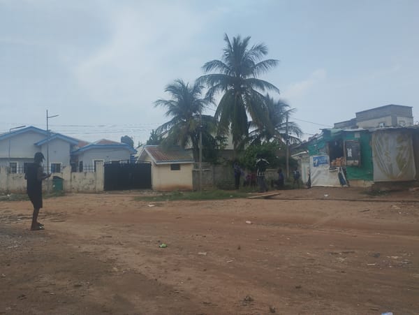 Man uses phone on dirt road in Gwarinpa, Nigeria