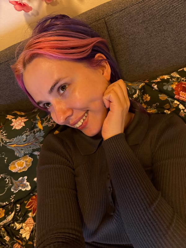 Woman with colorful hair relaxes on couch in Zagreb