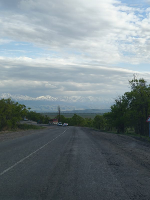 Vehicle travels mountain road in rural Kyrgyzstan