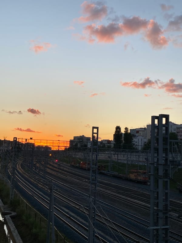 Train yard at golden hour, tracks stretching into the sunset