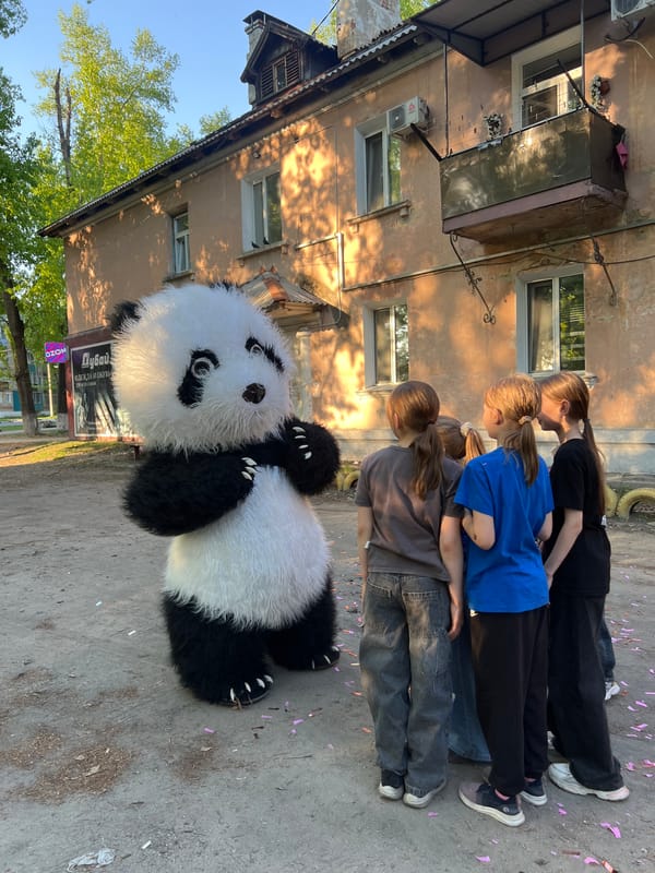 Panda mascot entertains children in outdoor gathering
