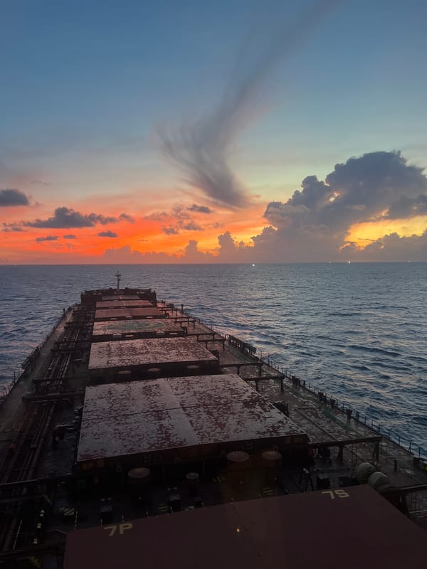 Cargo ship cuts through calm seas at sunset