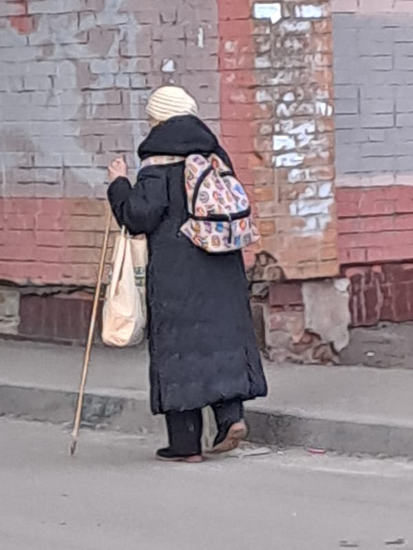 Woman walks with walking stick on Elektrostal sidewalk