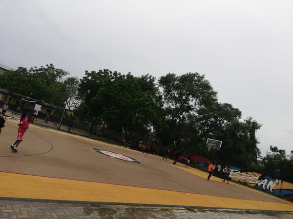 Young people play basketball at Lagos court during overcast afternoon