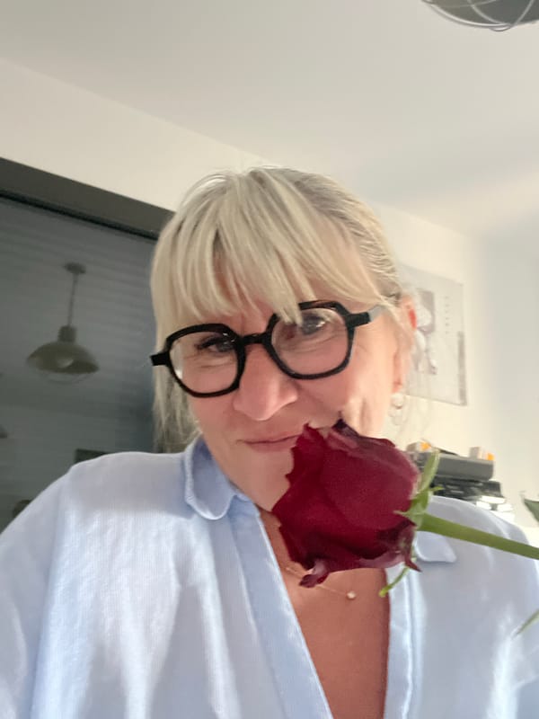 Person smells red rose in Chambœuf, France morning scene