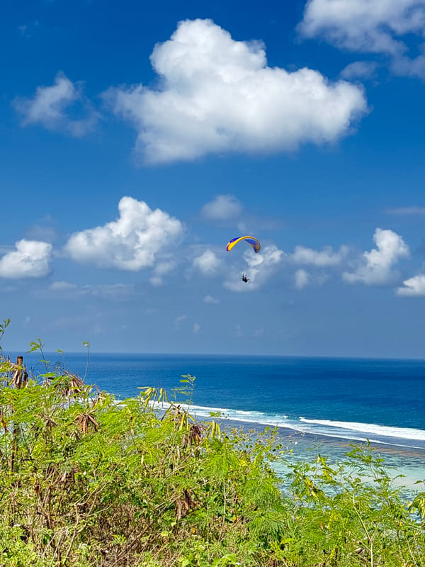 Paragliders fill the sky above Kuta Selatan's coastal cliffs