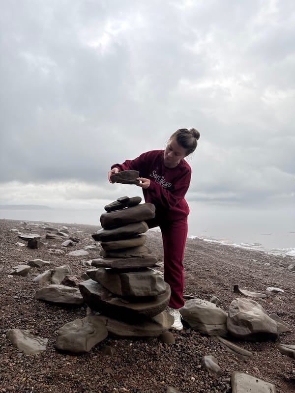 Woman builds rock cairn on Russian beach