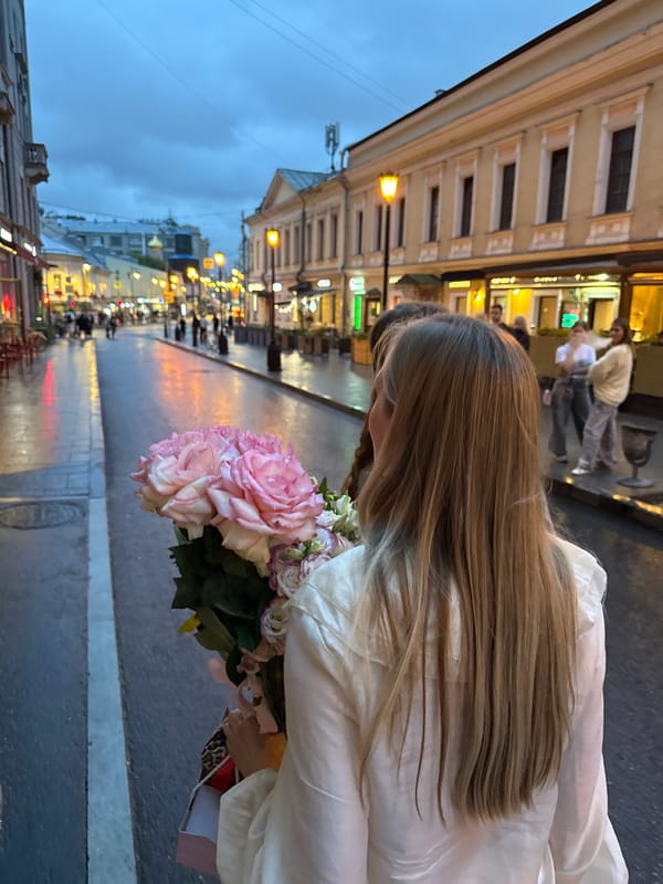 Pale pink roses on a rain-slicked Moscow evening street