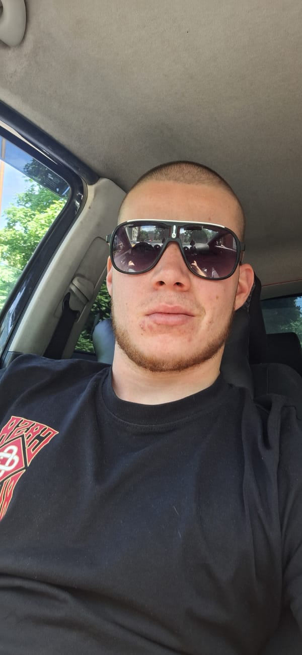 Man in sunglasses sits in vehicle near greenery in Burgas