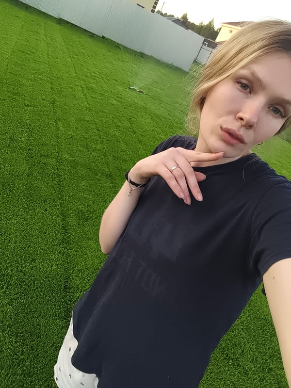 Woman and boy pose playfully on lawn in Russian village