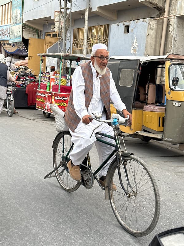 Elderly man cycles through Quetta streets in traditional dress