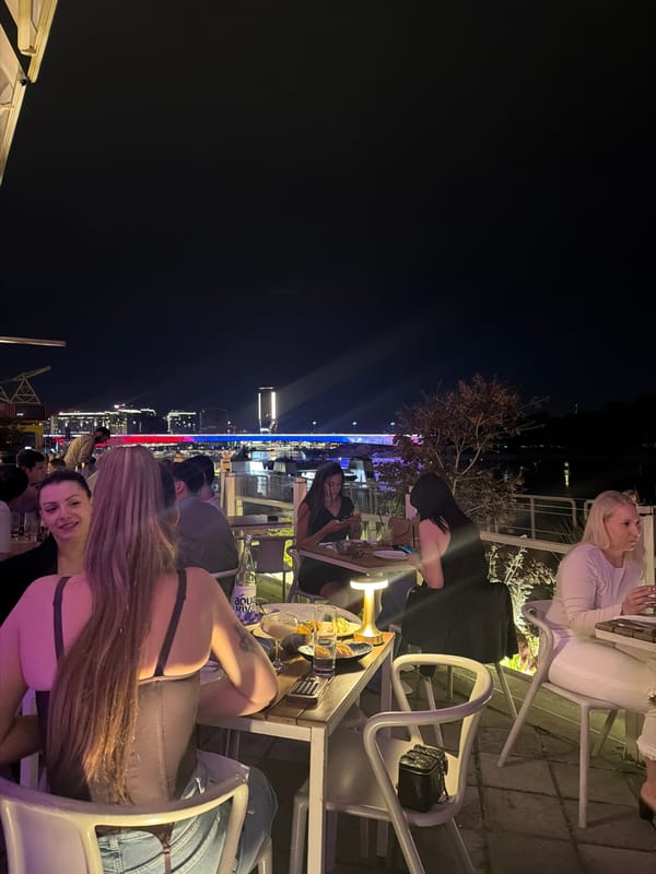 Evening rooftop dining gathering overlooks illuminated Belgrade skyline
