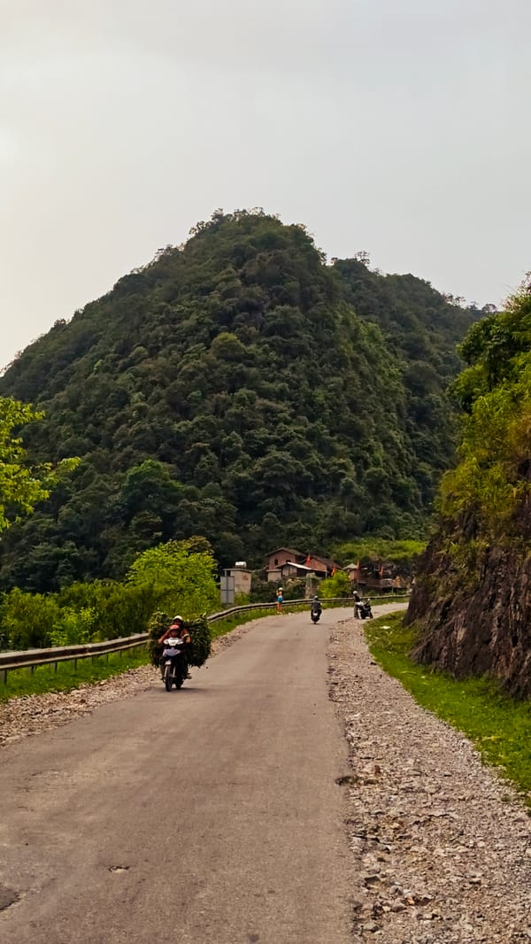 Motorcyclist travels mountain road in rural Vietnam commune