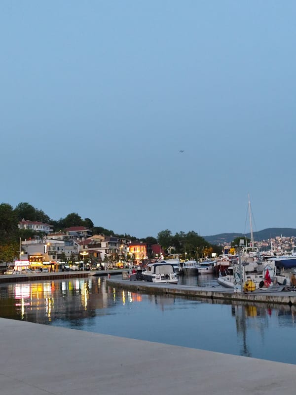 Sarıyer harbor at dusk, boats docked along a calm waterfront