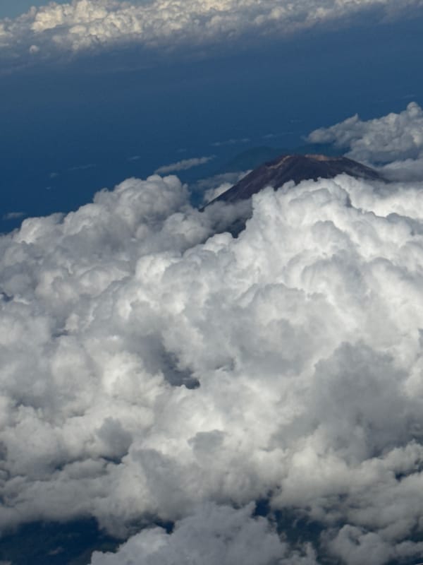 Aircraft passenger witnesses clouded mountain peaks over Bangli, Indonesia