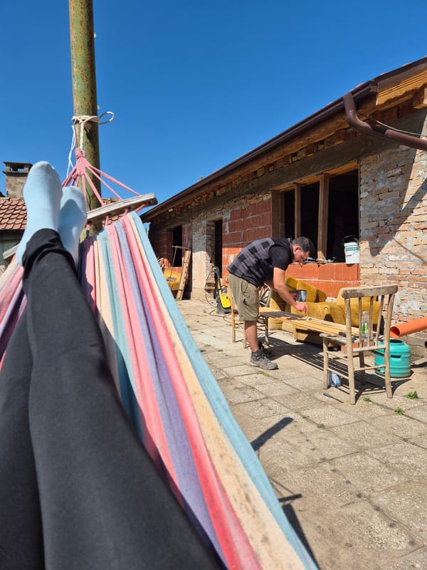 Man sands furniture outside brick building in Bulgarian village