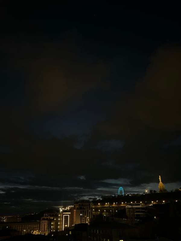 Evening lights illuminate Yerevan buildings under cloudy skies