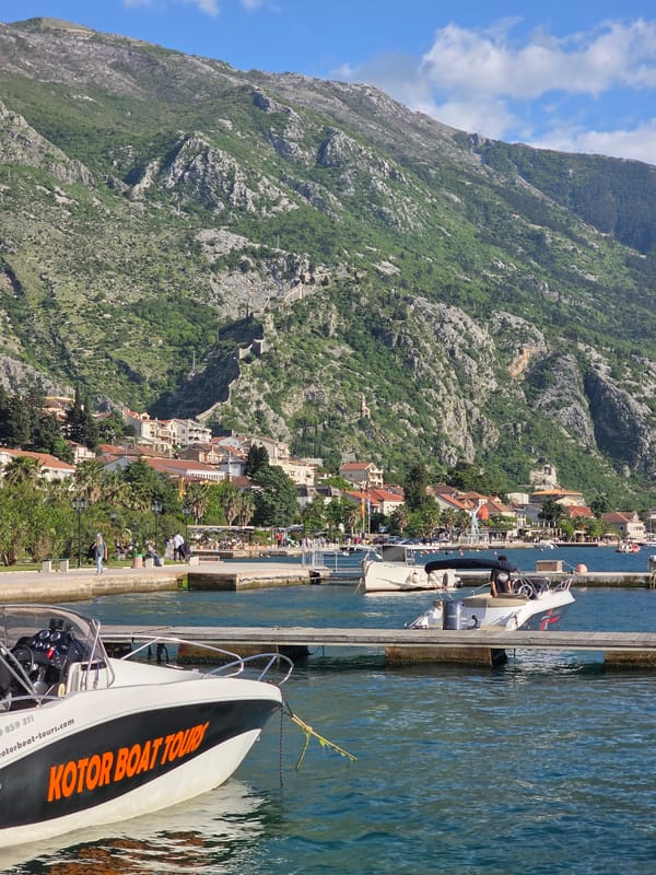 Tourists relax along Dobrota waterfront near historic Kotor walls