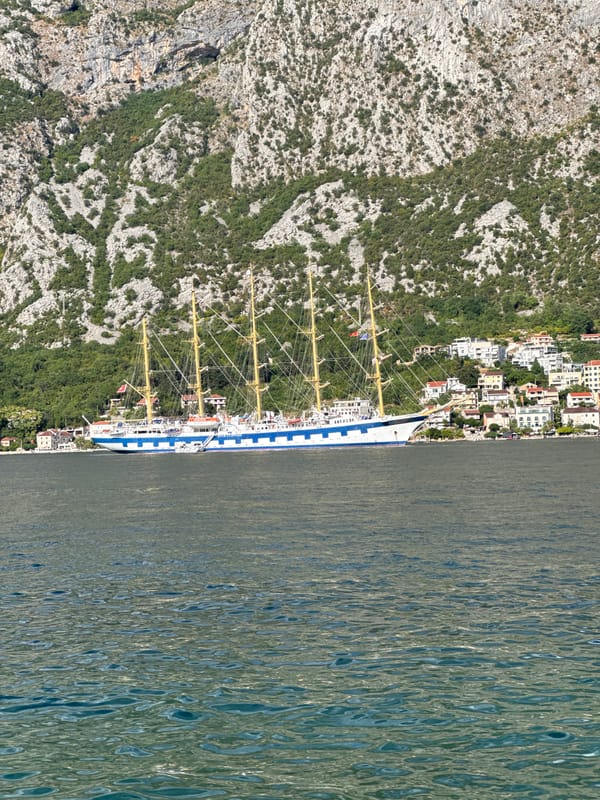 Tall ship anchored in Prčanj bay, locals lounging waterside
