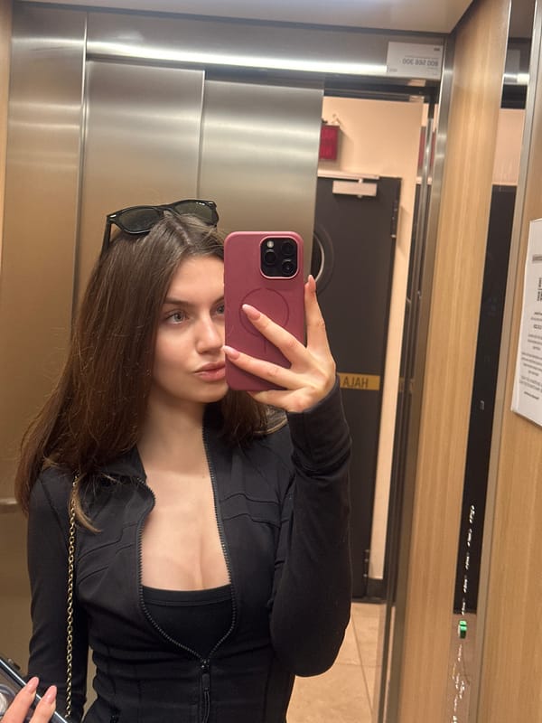 Woman takes selfie in elevator with pink phone