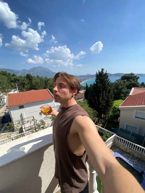 Man enjoys drink on sunny balcony in Montenegro coastal town