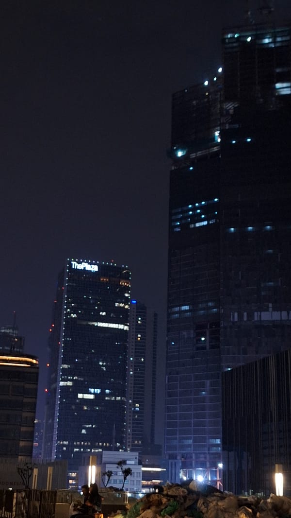 Jakarta skyline illuminated at night with ThePlaza building visible