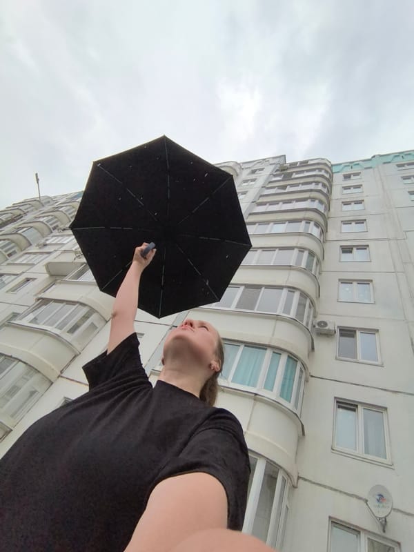 Person holds umbrella skyward in cloudy Froly, Russia