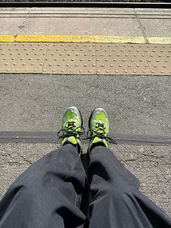 Commuter in green sneakers waits on London train platform