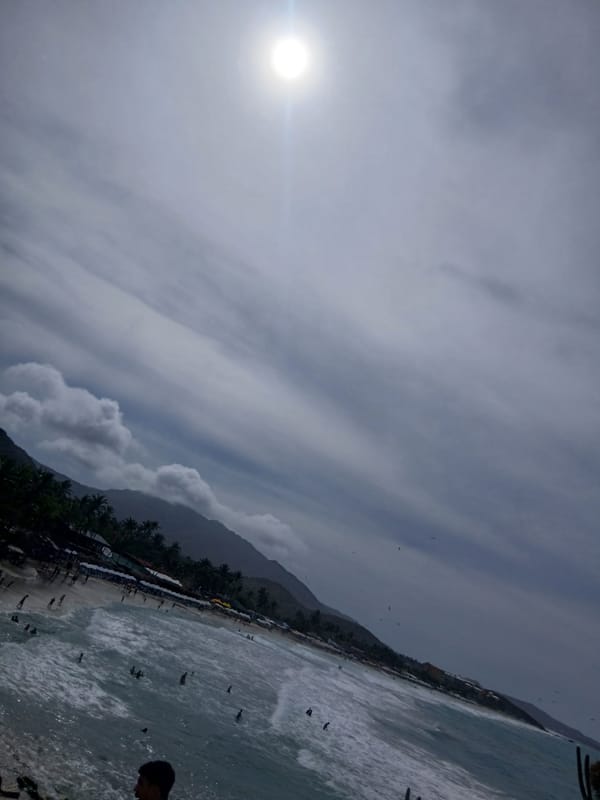 Beachgoers gather at Playa Parguito under cloudy Venezuelan skies
