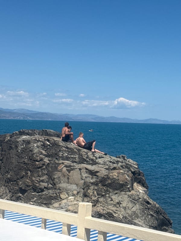 Beach morning with paddleboards, rocky coastline, and kids