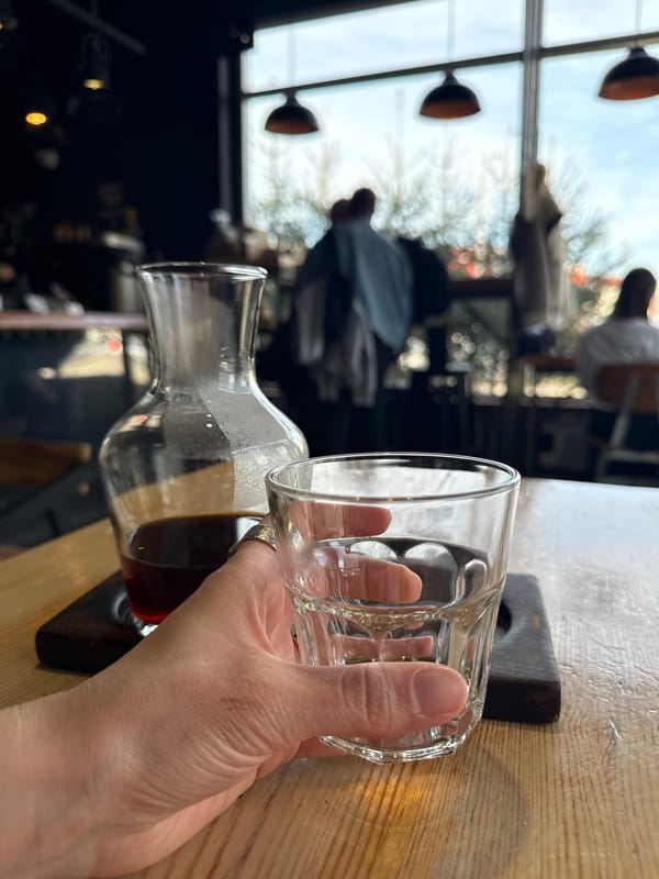 Person pours dark liquid from carafe into glass in Kazan