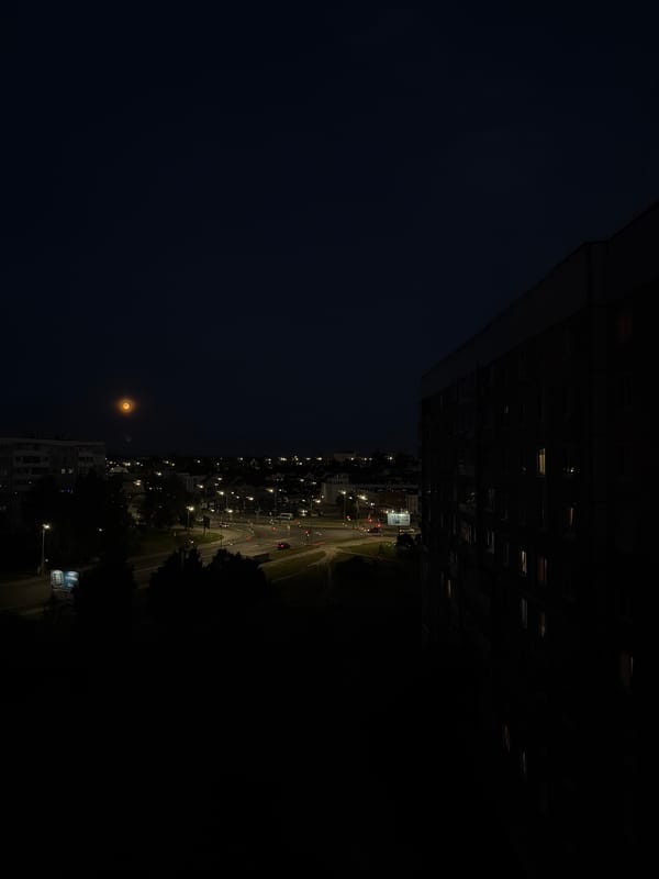 Orange moon rises over Mahilyow residential streets at dusk
