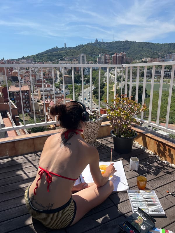 Woman paints from balcony overlooking Barcelona cityscape